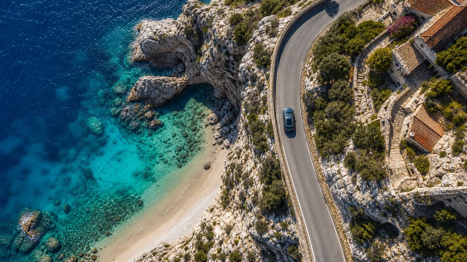 Automobile vista dal drone su una strada costiera italiana con mare e piccola spiaggia